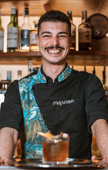 bartender smiling behind the bar with cocktail