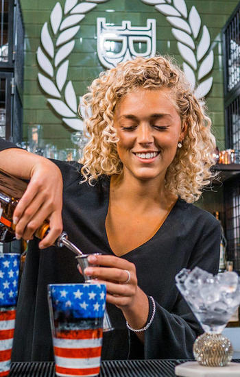 female bartender pouring spirit in jigger